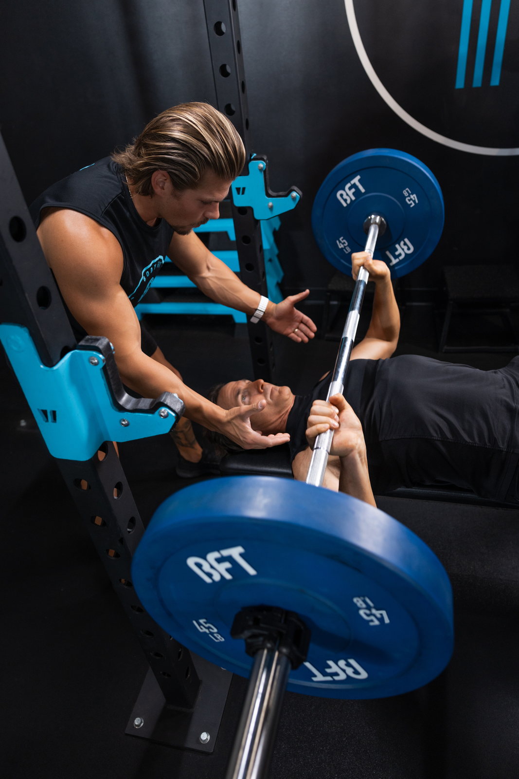 A BFT coach correcting a member's bench press form